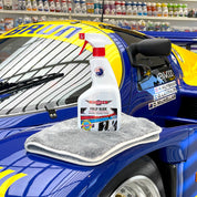 Car detailing products including a spray bottle and towel on a race car in a garage setting.