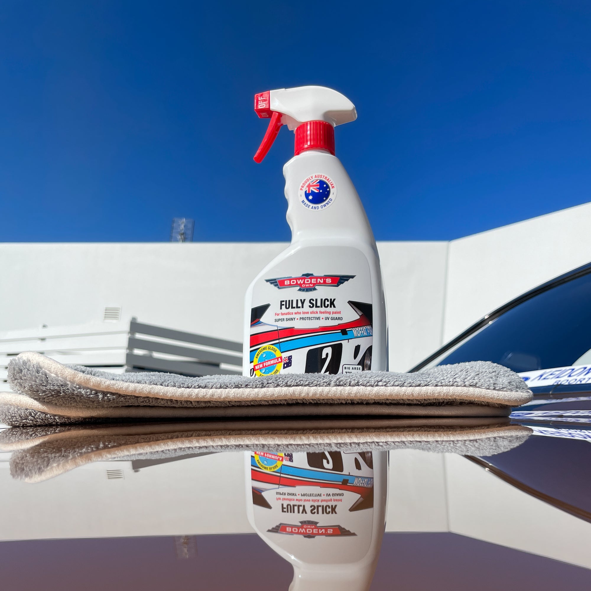 Banksys Fully Slick car care product on a car hood with a clear blue sky background