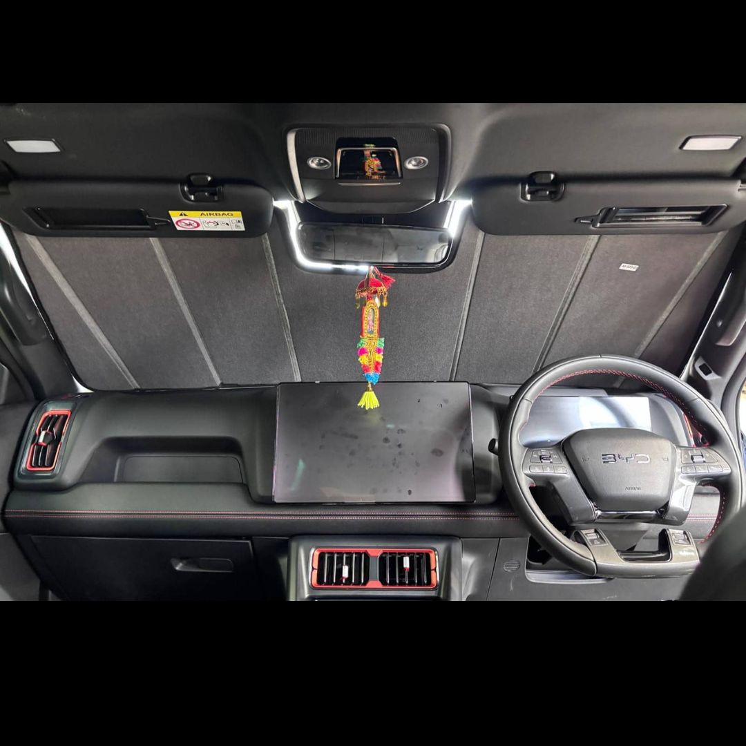 Car interior with dashboard and steering wheel, featuring a decorative item hanging from the rearview mirror.