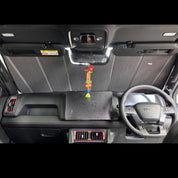 Car interior with dashboard and steering wheel, featuring a decorative item hanging from the rearview mirror.